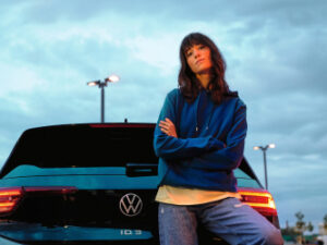 A woman leans over the windshield of a volkswagen